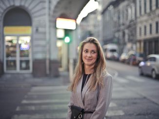 Woman smiling confidently in urban Budapest street scene with vibrant evening lights.